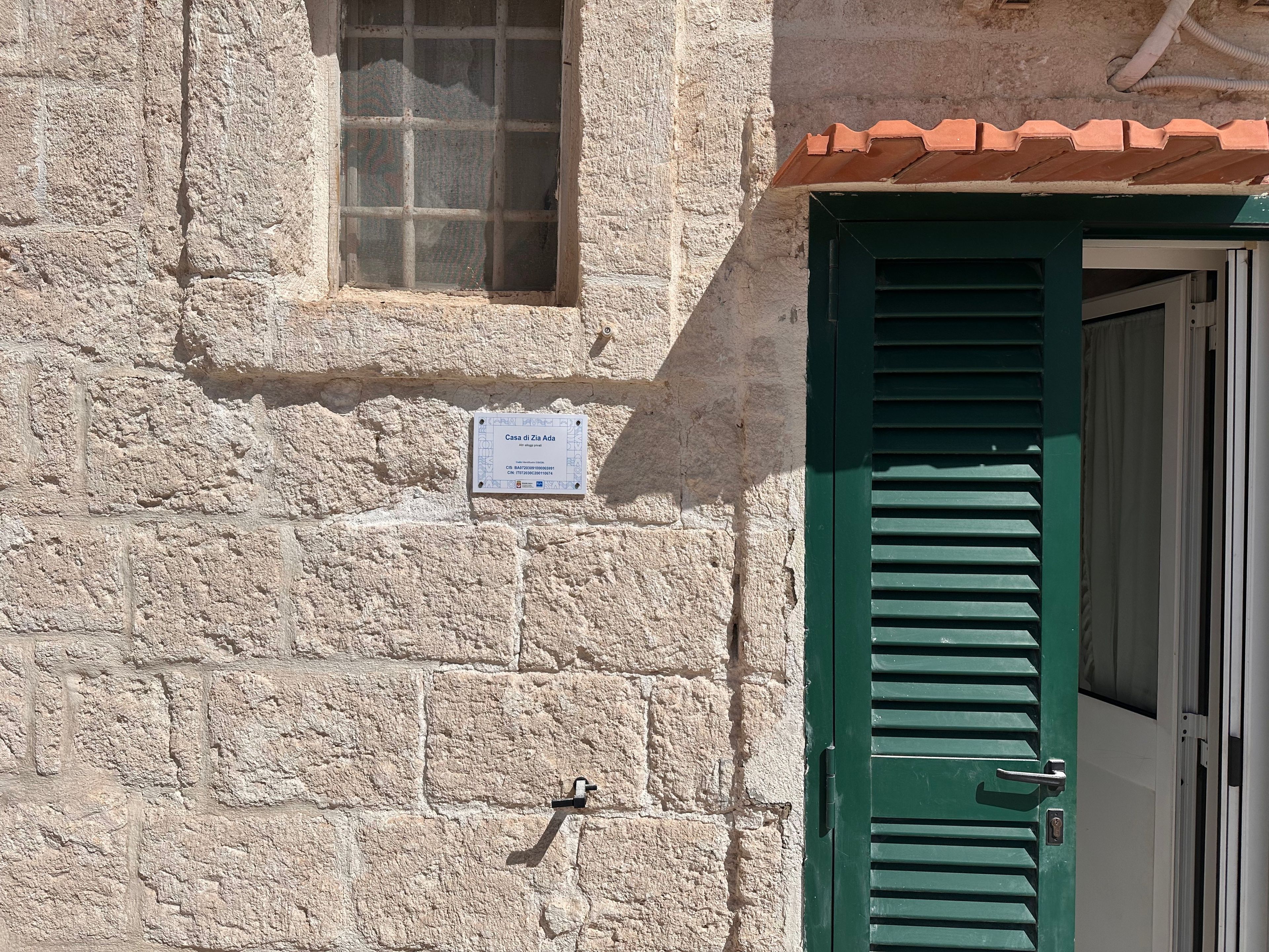 A stone building with a green door and a window.