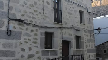 A two-story stone building with a balcony and a dog in front.