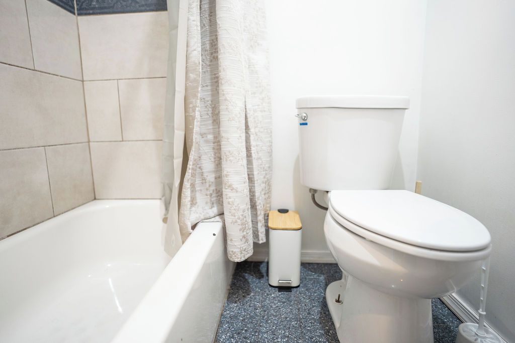 Un baño con bañera, inodoro y un cubo de basura.