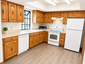 Una cucina con mobili in legno, un forno a microonde, un forno e un frigorifero.