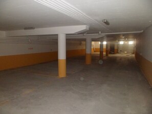 Een parkeergarage met betonnen vloeren en witte zuilen.