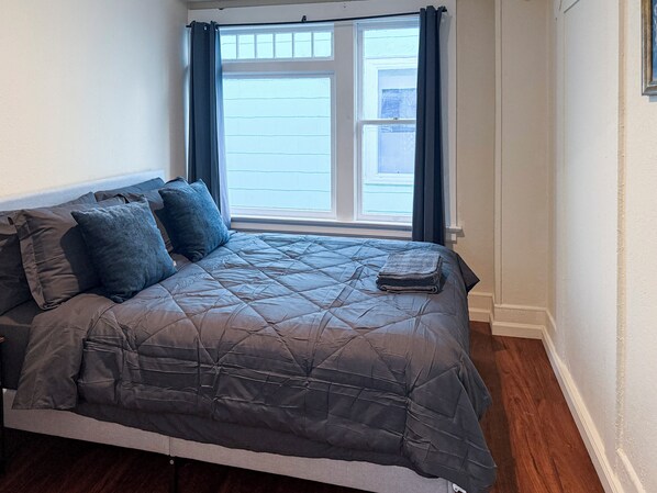 A bedroom with a bed, dark curtains, and a window with blinds. - Downtown 3BR w/ AC & Parking Mins to SJSU & SAP (San Jose)