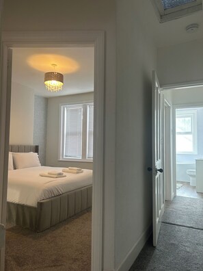 Une chambre à coucher avec un lit, un lustre et une fenêtre avec des stores.