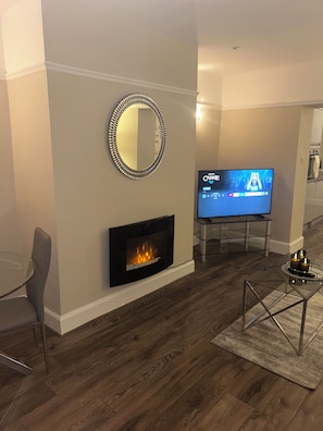 A living room with a fireplace, a television, and a modern chair.