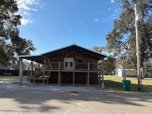 A wooden cabin with a covered porch and a fenced yard. - Eagle Lake Hunting and Fishing Cabin (Vicksburg)