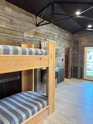 A bunk bed with a striped mattress, a wooden headboard, and a small shelf with a framed picture. - Eagle Lake Hunting and Fishing Cabin (Vicksburg)