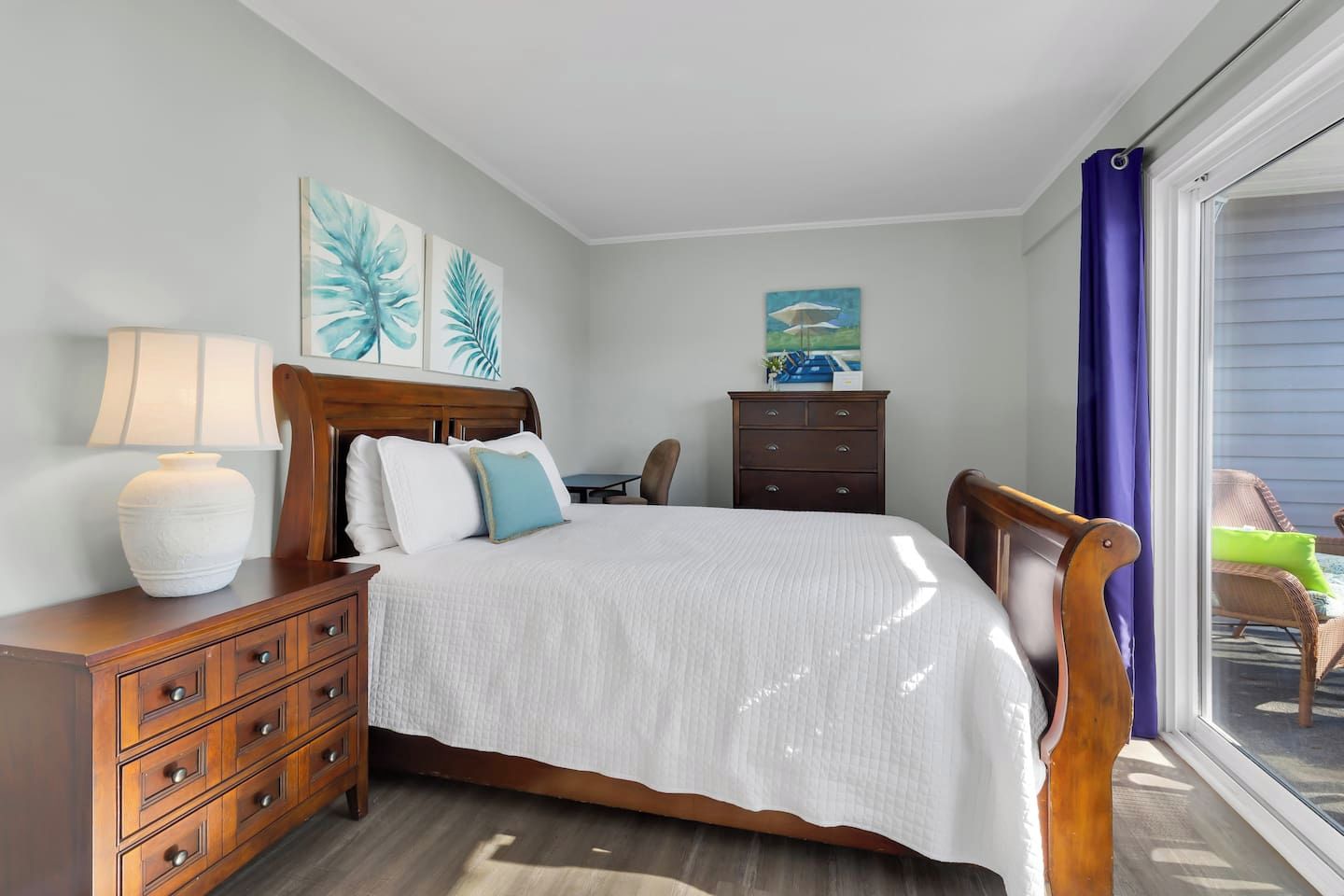 Une chambre à coucher comprenant un lit, une table de chevet, une commode, une chaise et une fenêtre donnant sur un beau paysage.