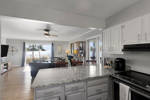A modern kitchen with granite countertops, white cabinetry, and a built-in stove. - River`s Edge Retreat (New Bern)