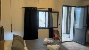 Habitación de hotel con cama, un espejo grande, una araña y vistas a través de una puerta abierta.