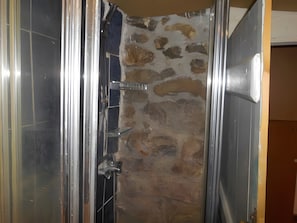 Un vano con pared de piedra y marco de puerta metálico.