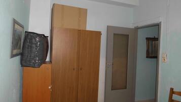 Una habitación con un armario de madera, una puerta cerrada y un cuadro en la pared.