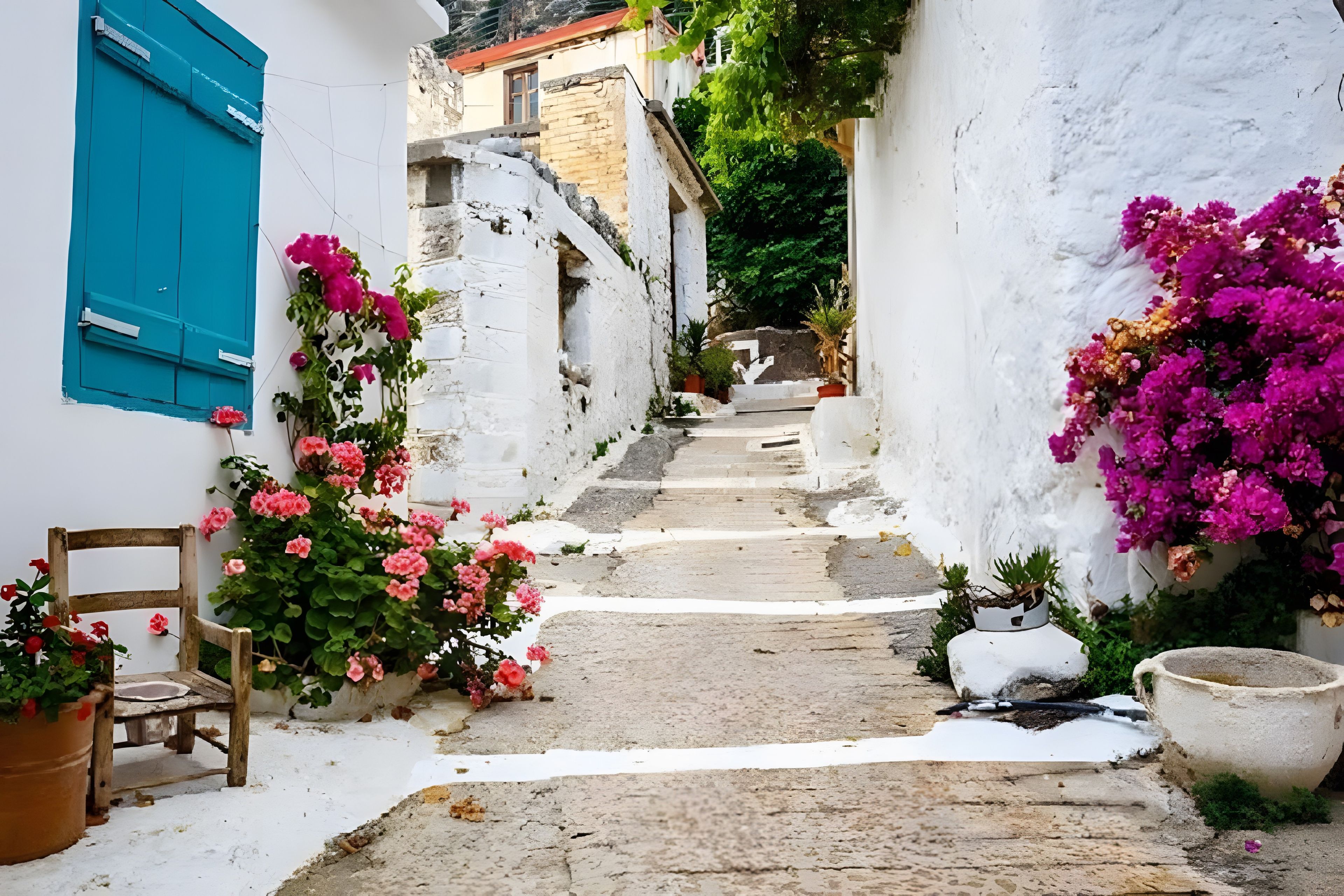 Eine schmale Gasse mit weiß getünchten Gebäuden, einem hölzernen Stuhl und Kübeln mit rosa Blüten.