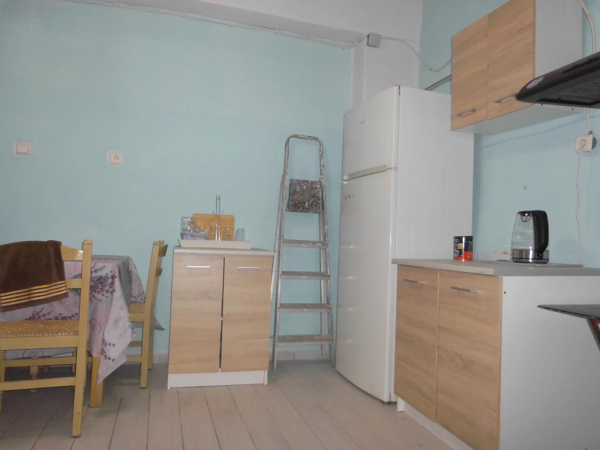 Una cocina funcional con armarios de madera, un refrigerador blanco, una mesa con mantel y una tetera en la encimera.