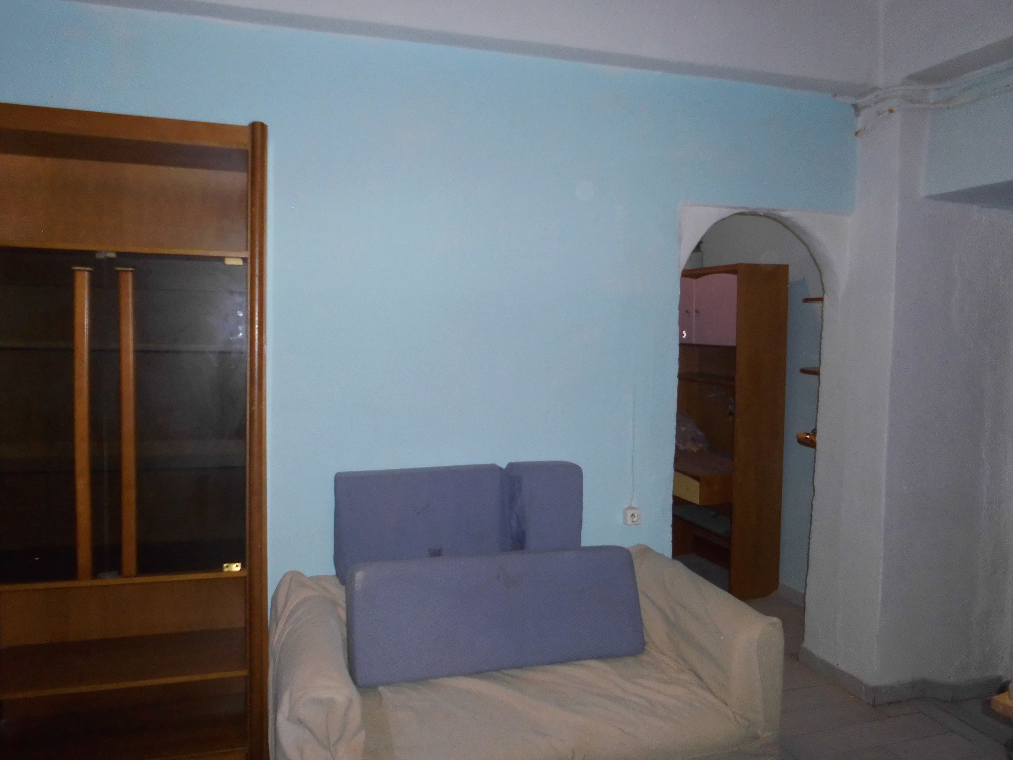 Ein Zimmer mit einem Bett, einem Kleiderschrank und einer Tür zu einem anderen Raum.