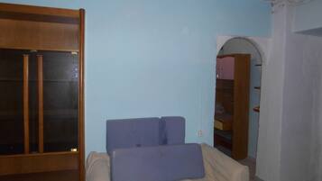Ein Zimmer mit einem Bett, einem Kleiderschrank und einer Tür zu einem anderen Raum.