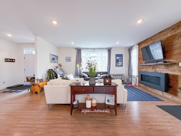 A living room with a sofa, a coffee table, a fireplace, and a television mounted on the wall. - Unit A/ Spacious/ Heated pool/ Close to beach/ On-site Activities! (Brackley Beach)