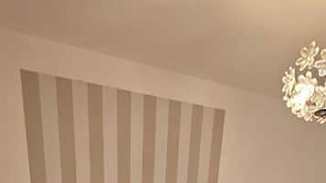 Una camera da letto con un letto grande, due comodini, un termosifone e una parete a righe.