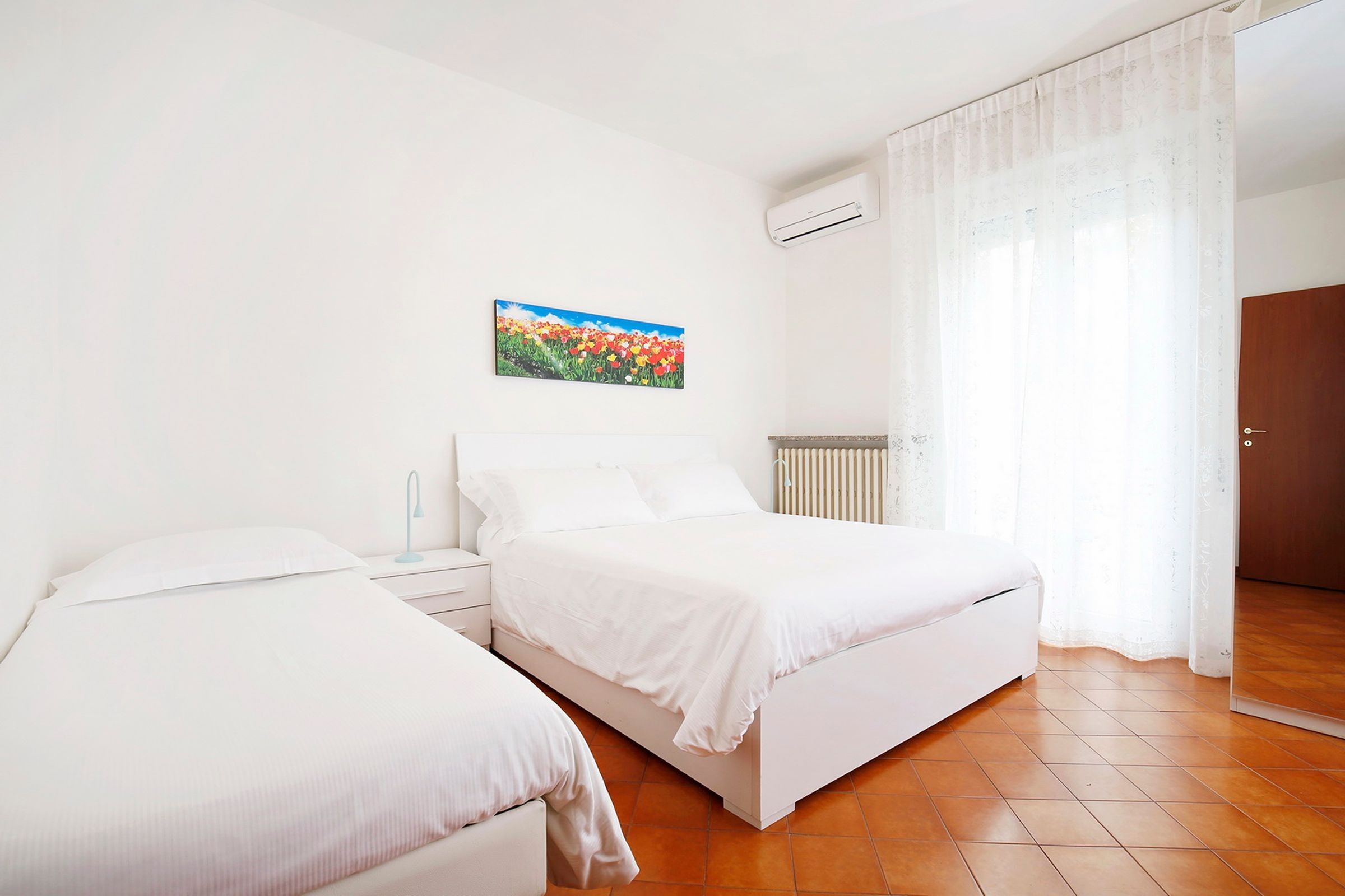 Un dormitorio con dos camas, un radiador y una ventana con cortinas.