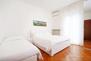 Un dormitorio con dos camas, un radiador y una ventana con cortinas.