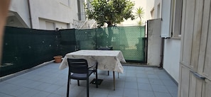 A small outdoor patio with a table and chairs, surrounded by a green fence and a white building. - Apartment 'Rosa Appartamenti Pellico' with spacious ground floor and outdoor area (Cattolica)