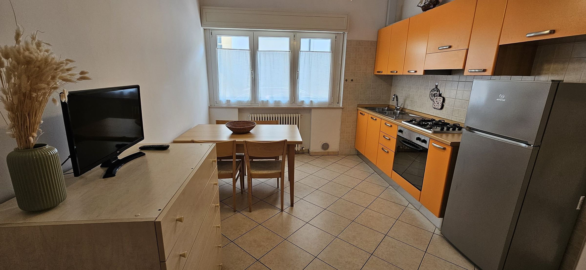 A compact kitchen with a dining table, chairs, a stove, and a refrigerator.