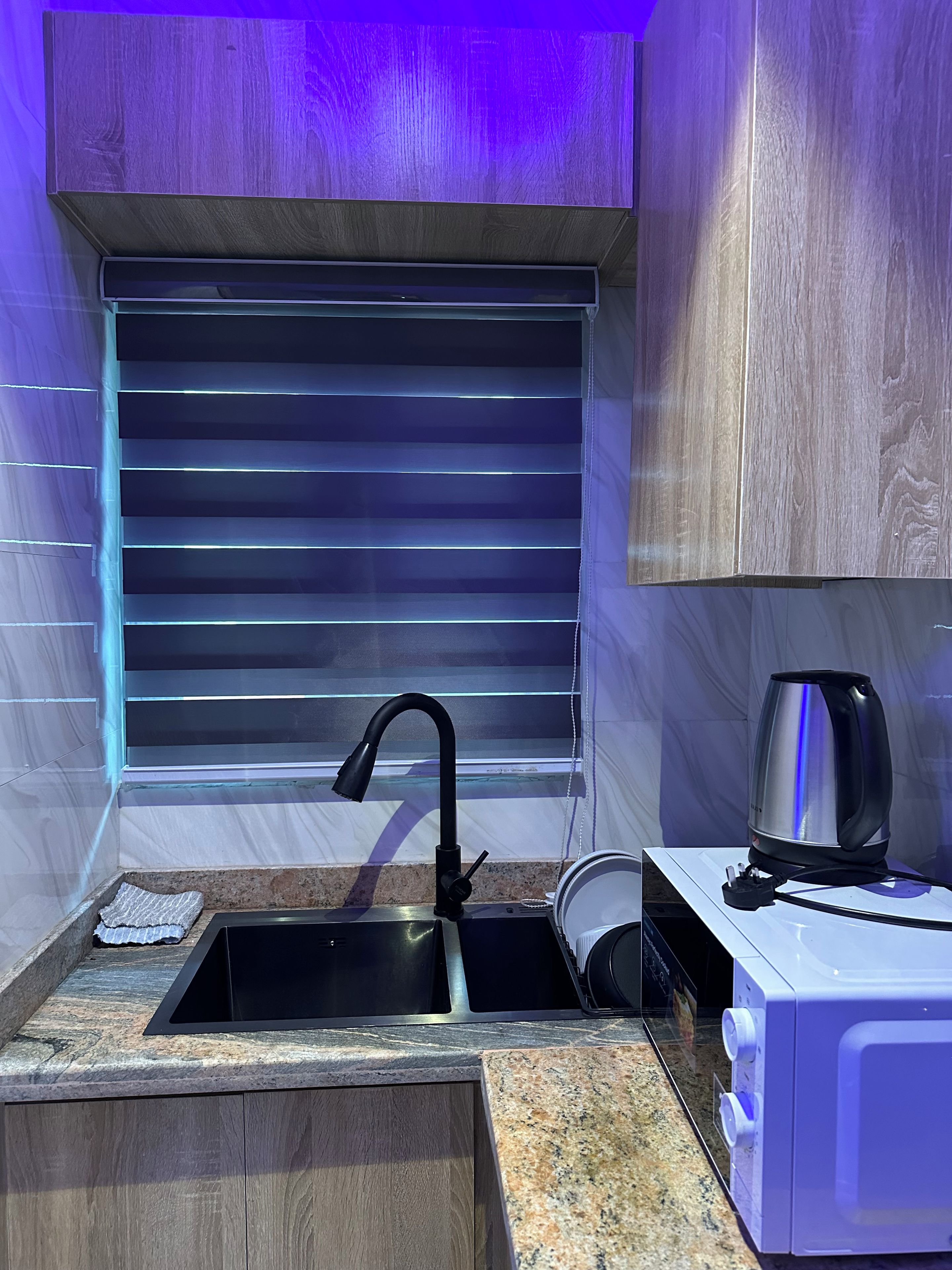 A compact kitchen with a built-in sink, a kettle, and a small countertop.