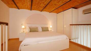 A bedroom with a wooden ceiling, a bed with white bedding, two bedside lamps, and a window with blinds.