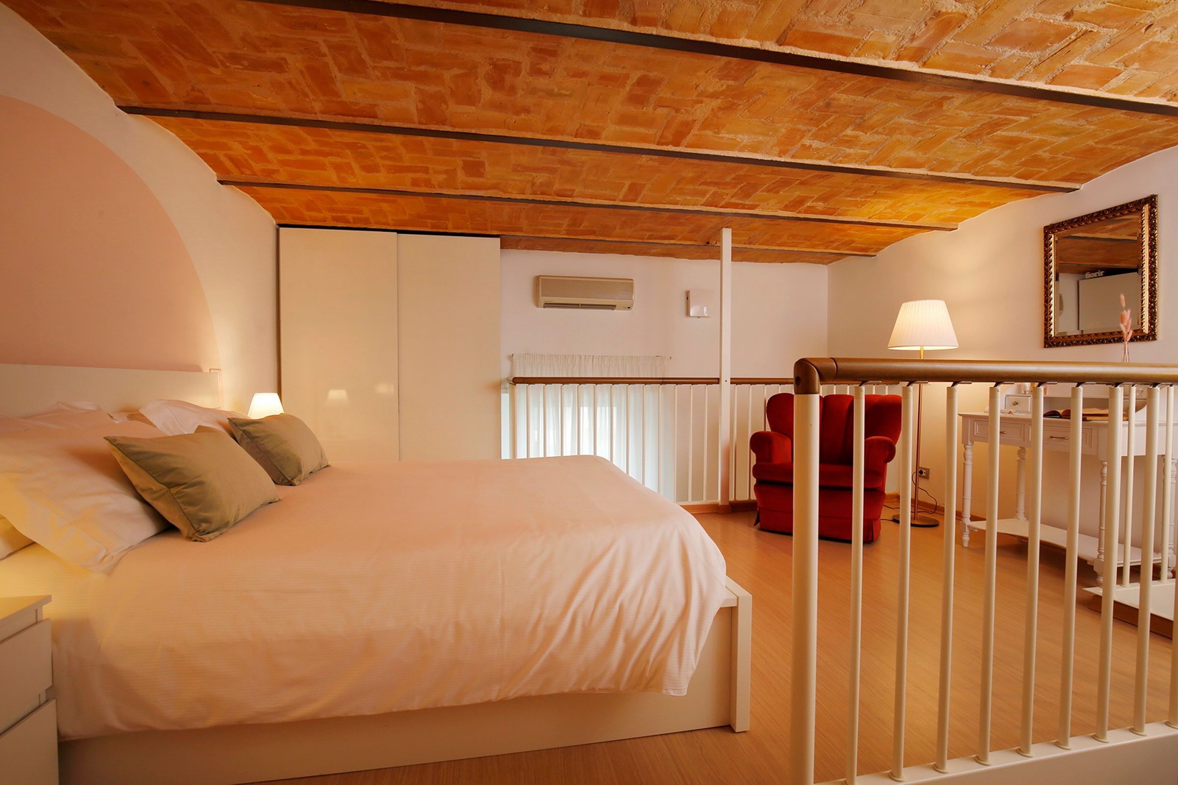 Un dormitorio con una cama, una silla roja, un escritorio y un espejo.