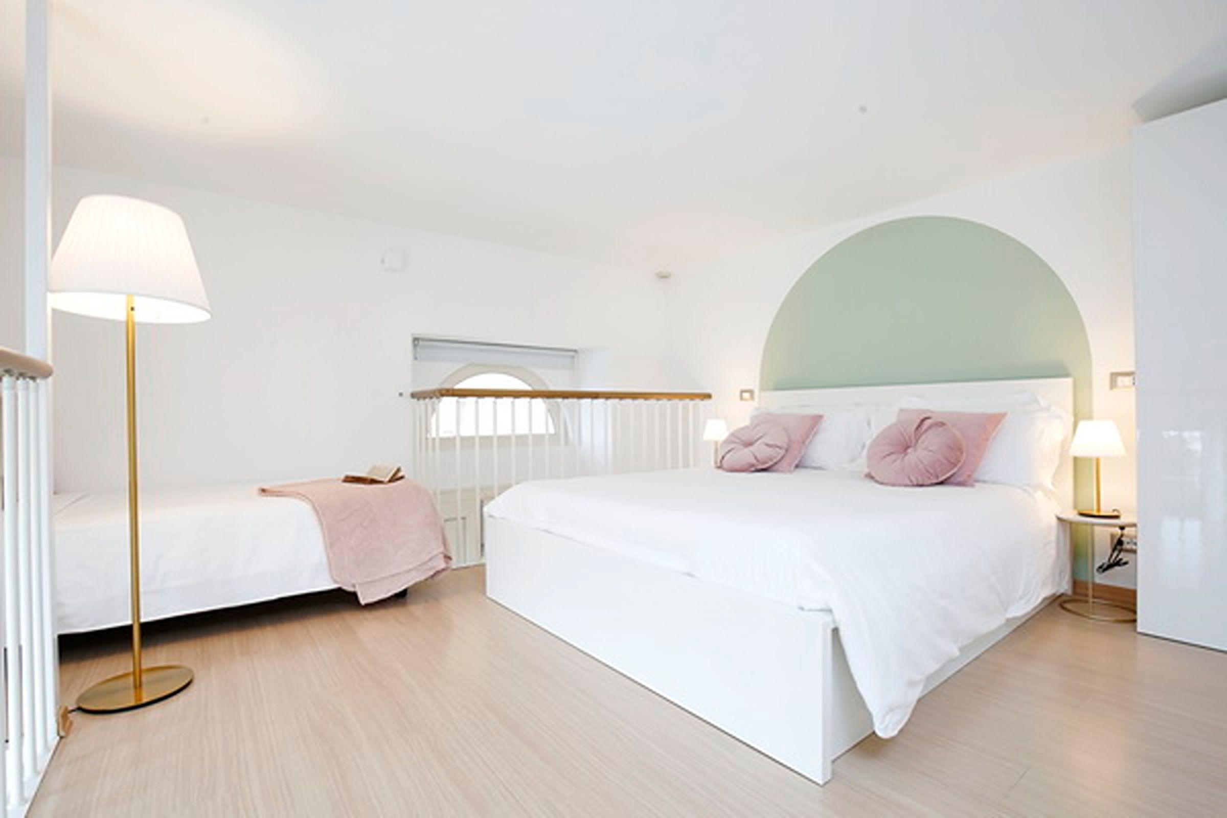 Una camera da letto moderna con un letto grande, un letto più piccolo e una lampada da terra.