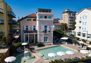 Een hotel met een zwembad, terras en uitzicht op omliggende gebouwen.