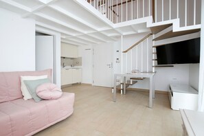 Un interior moderno con una escalera, un sofá rosa y una zona de cocina.