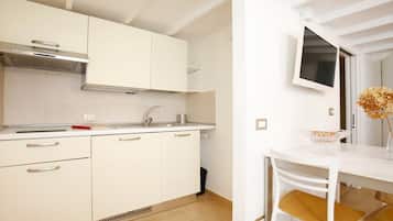Una cucina moderna con mobili bianchi, piano cottura integrato e zona pranzo con tavolo e sedie bianche.