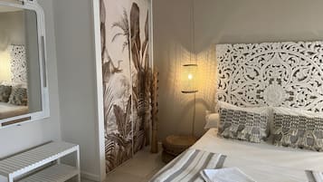 A bedroom with a bed, a bedside table, a decorative headboard, a wall with a floral mural, and a hanging light fixture.