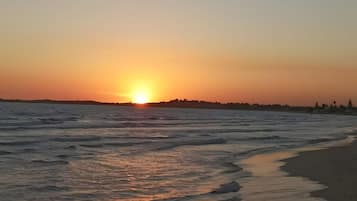 A sunset over a beach with waves gently lapping onto the shore.