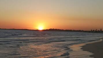 A sunset over a beach with waves gently lapping onto the shore.