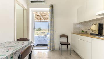 Una cucina compatta con angolo ristoro, una macchina per caffè e vista su un patio esterno attraverso una porta.