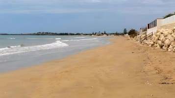 Una spiaggia sabbiosa con una parete rocciosa e cielo sereno.