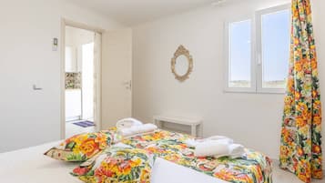 Une chambre à coucher avec un lit, une table de chevet, un miroir et une fenêtre avec des rideaux.