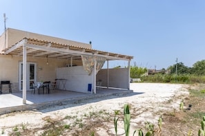 Un espacio al aire libre cubierto con una mesa y sillas, una puerta y una ventana.