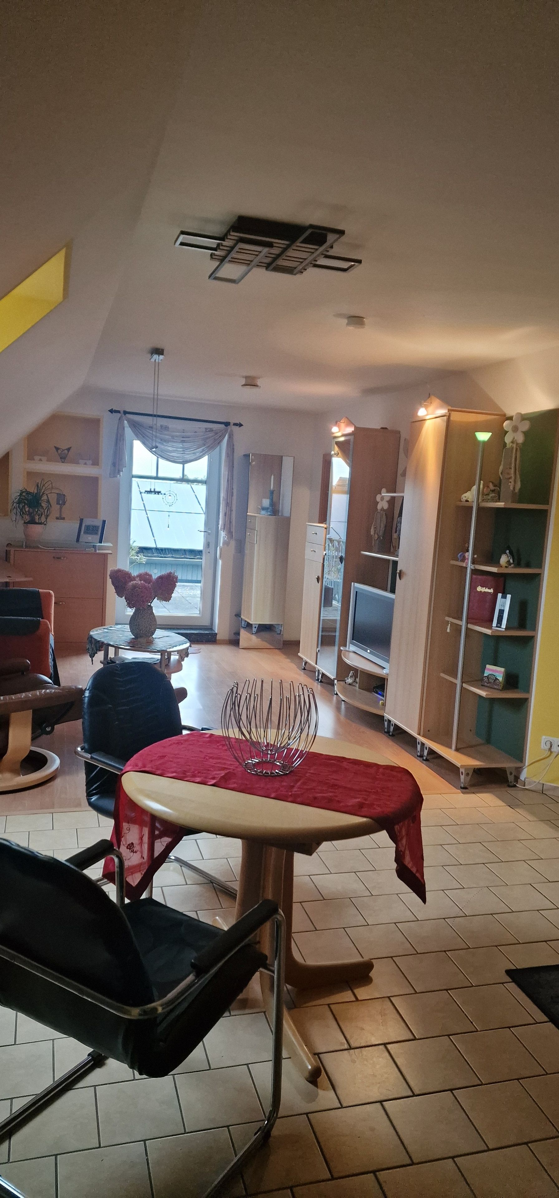 A spacious living area with a dining table, a sofa, and a TV stand.