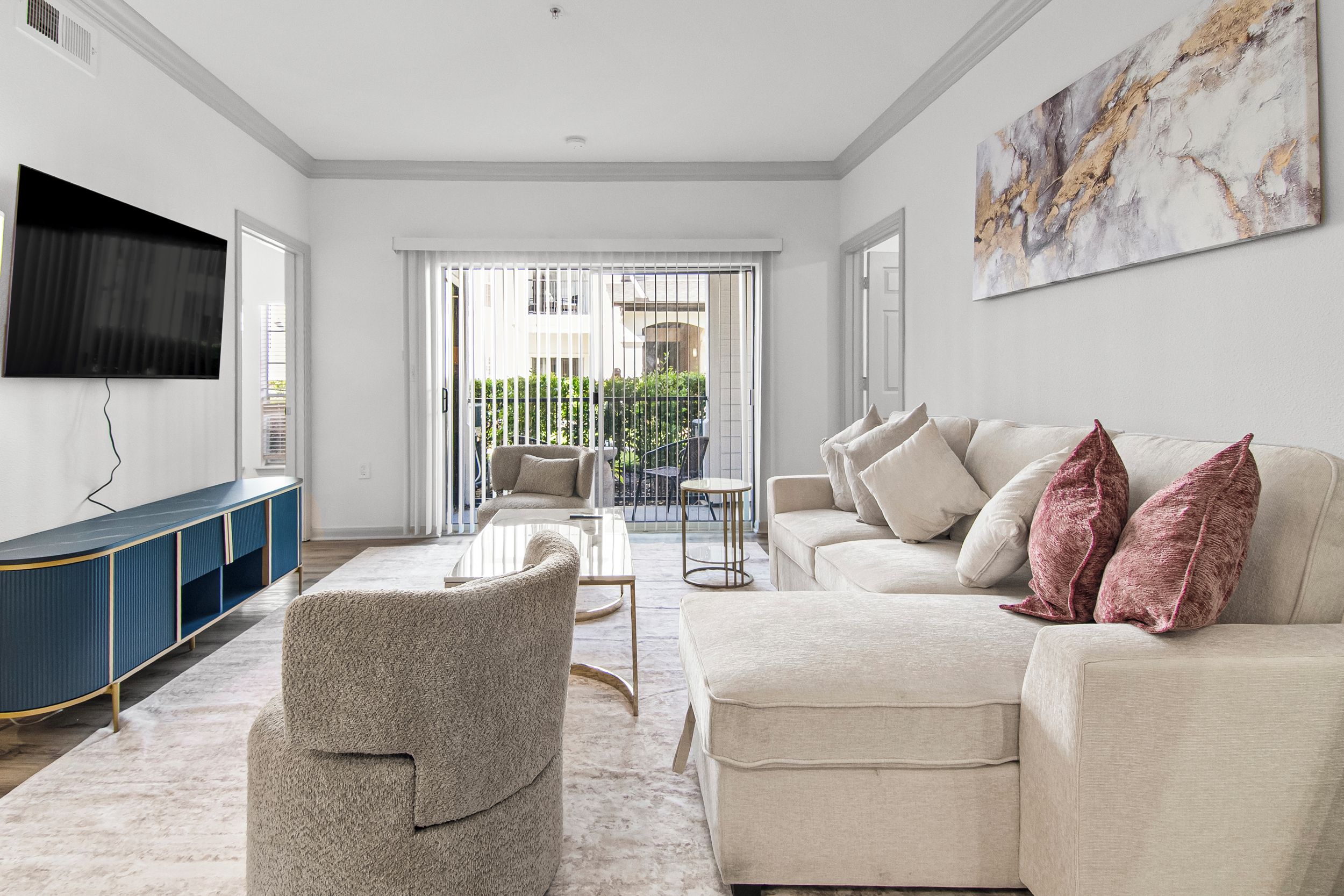 A modern living room with a flat-screen TV, a sofa set, a coffee table, and a patterned rug.