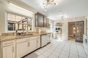 A kitchen with white cabinets, a granite countertop, a built-in dishwasher, and a window with a view. - 585 Orange Grove Ave (Melbourne)