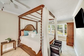 A four-poster bed with a canopy, a bedside table with a plant, and a view of the outdoors through a window. - 585 Orange Grove Ave (Melbourne)