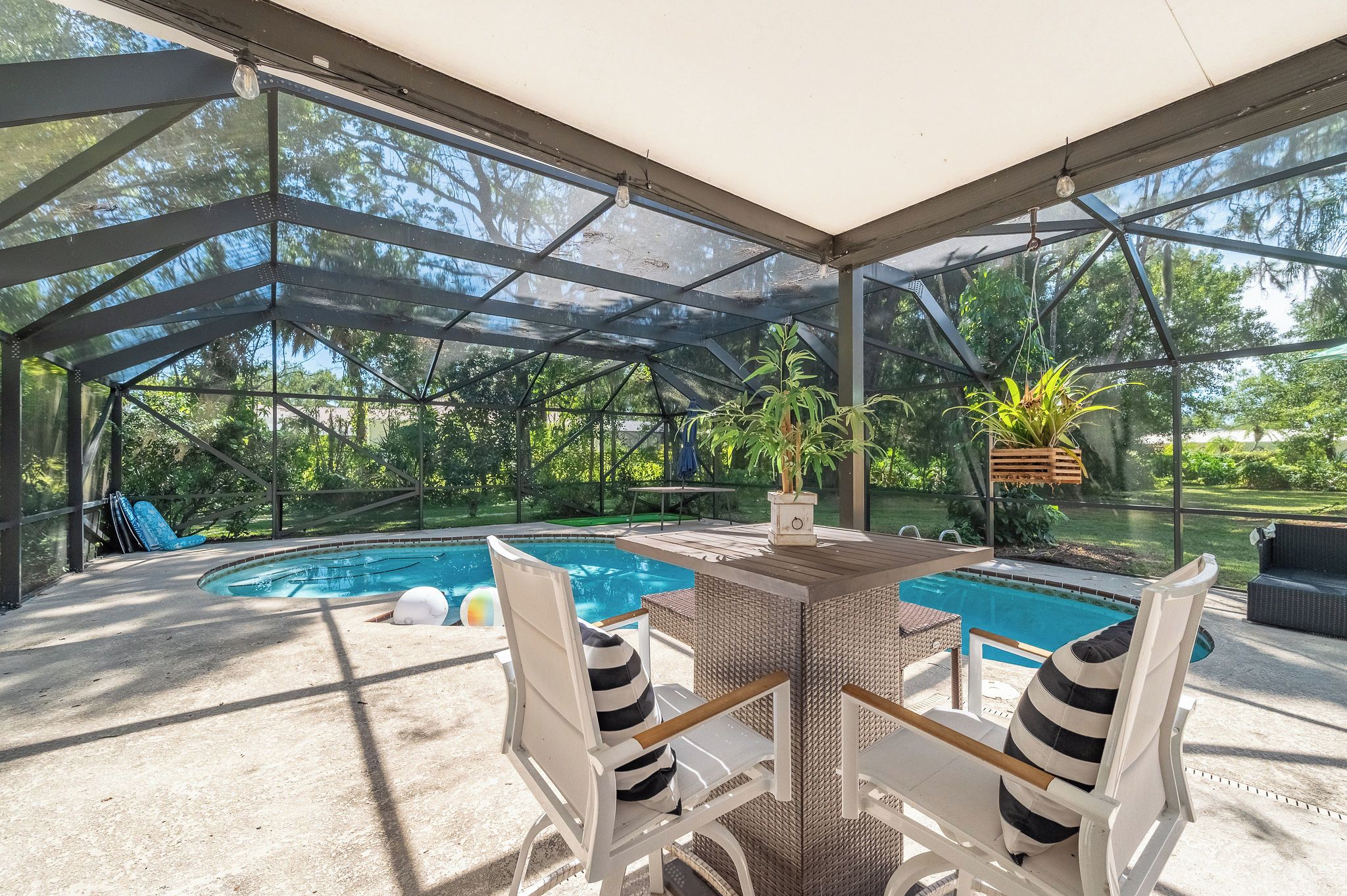 A covered outdoor area with a pool, seating, and potted plants.