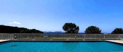 A swimming pool with lounge chairs and a view of the sea.