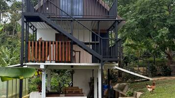 A two-story house with a balcony, surrounded by greenery.