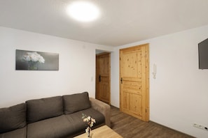 Una sala de estar con un sofá marrón, una puerta de madera y un cuadro en la pared.