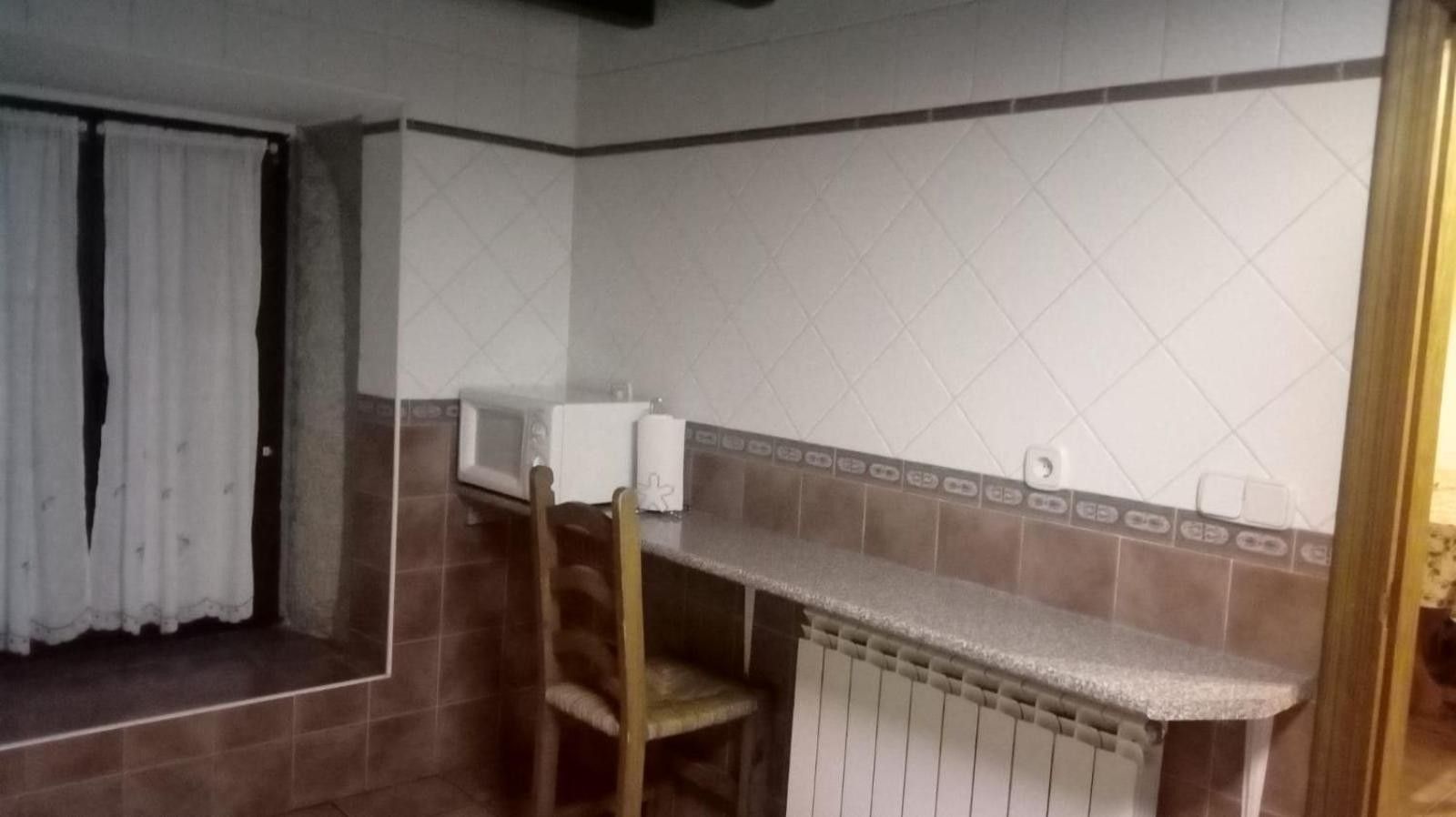 Een badkamer met een douche, toilet, wastafel en een stoel.