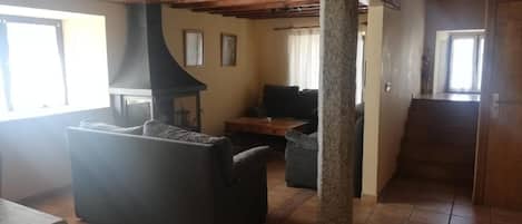 Una sala de estar con chimenea, un sofá, una mesa de centro y un pilar de piedra.