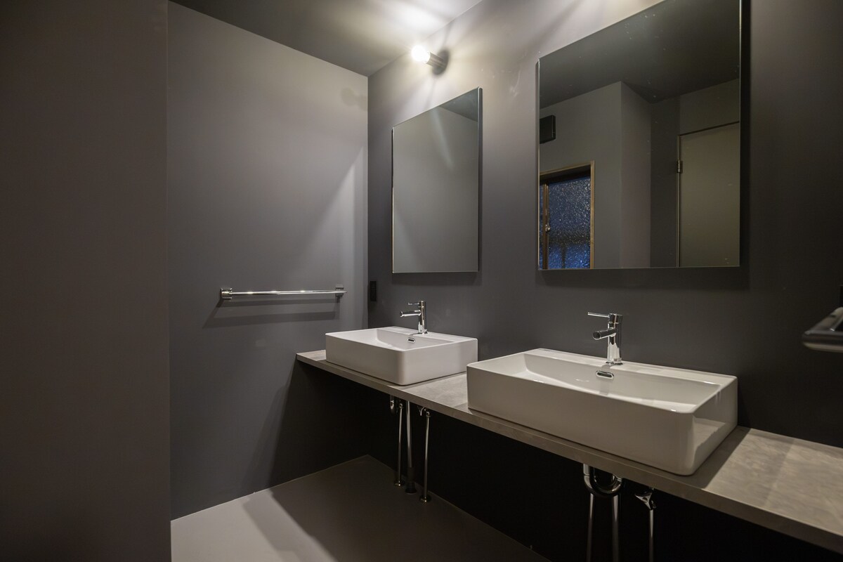 A modern bathroom with two sinks, a large mirror, and a towel rack.